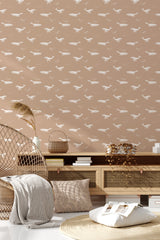 This wallpaper design has a soft beige background with repeat white whale silhouettes swimming in different directions, creating a serene and playful ocean-themed pattern. Traditional wallpaper.