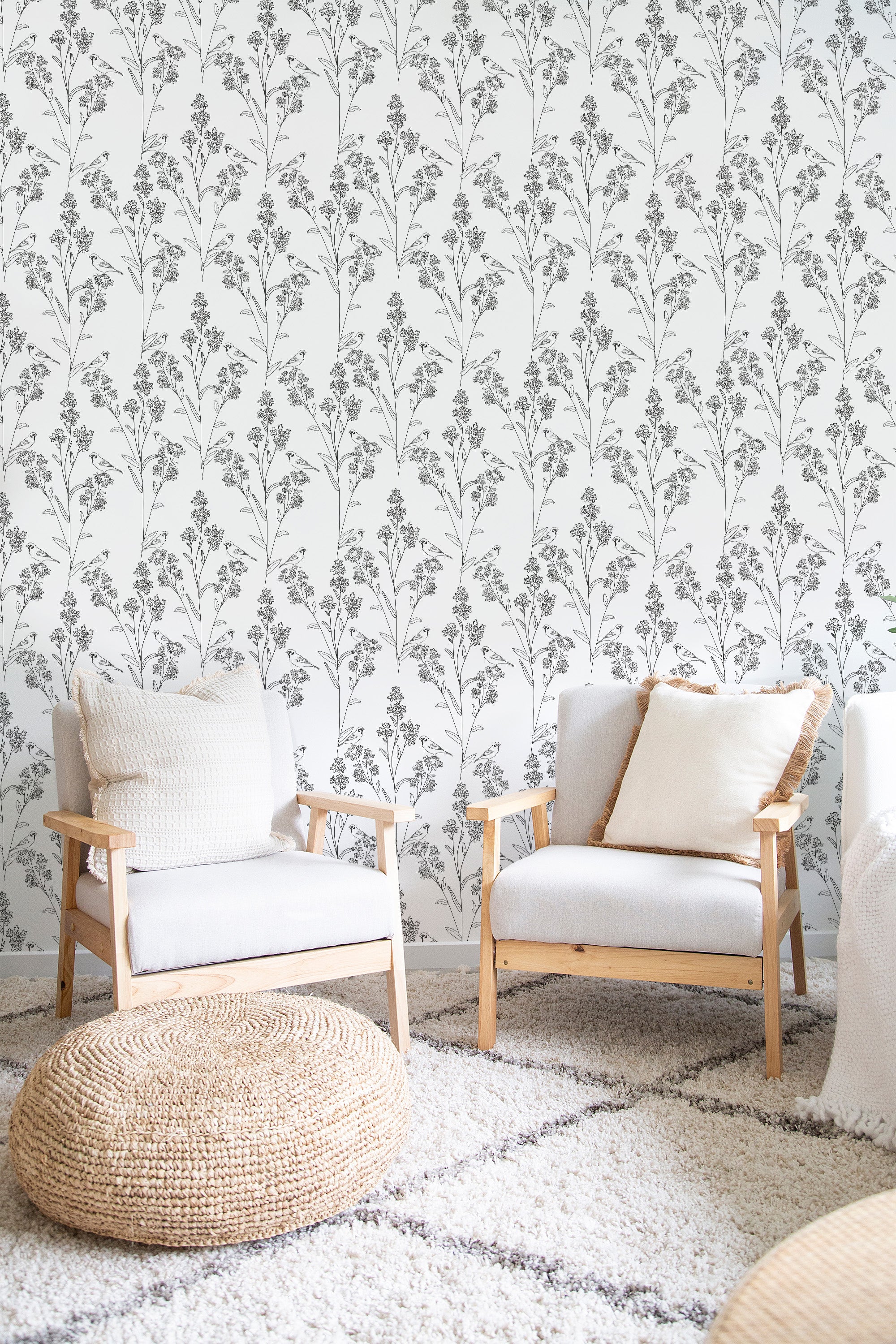 A room with light-colored Bird Meadow wallpaper with a repeating pattern of delicate, intricate floral branches and small birds on a neutral background, complementing the soft, cozy furnishings. Traditional wallpaper.