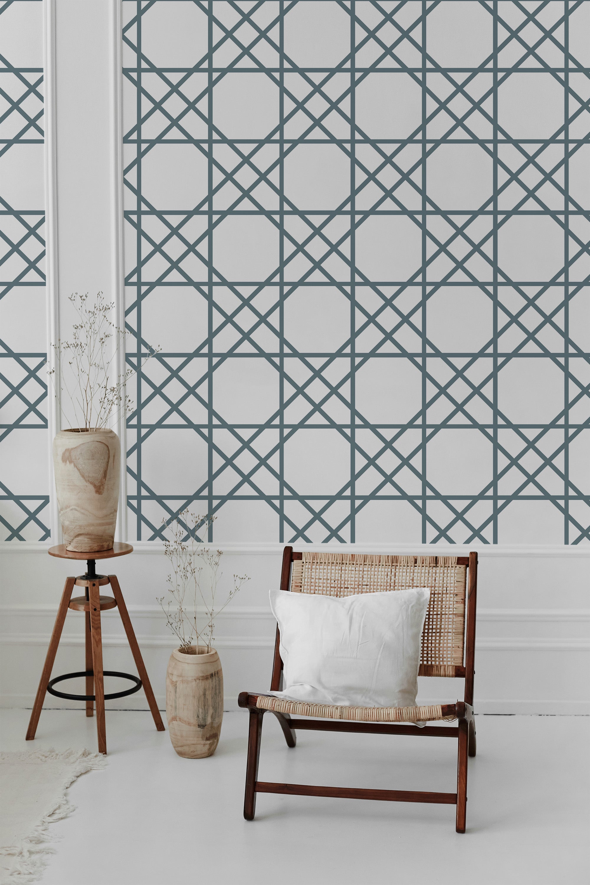 The wallpaper has a geometric pattern with intersecting lines forming a grid of diamond shapes in a muted blue tone. The design creates an intricate, lattice-like effect on a white background that exudes a clean and organized aesthetic, giving the room an elegant and classic ambiance. Traditional wallpaper.