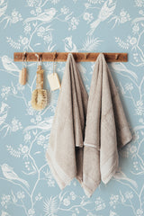 Self-adhesive light blue chinoiserie wallpaper with intricate white botanical patterns and birds.