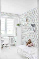 Pastel Aztec wallpaper in light shades of blue, gray, and yellow forms an intricate, geometric pattern with triangles, diamonds, and zigzags, complementing the modern and minimalist decor of the room. Traditional wallpaper.