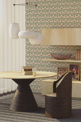 A room with wallpaper adorned in a Rose arch pattern, featuring rows of stylized floral motifs in shades of green and pink. The wallpaper complements the light wood furniture and a round table with a unique pedestal base, adding a classic and elegant touch. Traditional wallpaper.
