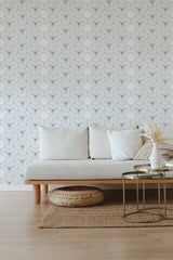 Abstract geometric print wallpaper with thin, intersecting lines creating a pattern of hexagons and triangles on a light background, covering the wall behind a simple and modern sofa in a cozy living room. Traditional wallpaper.