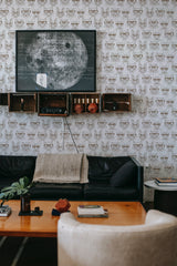 Wallpaper with a repeating pattern of sophisticated, stylized cat heads wearing glasses, providing a whimsical yet elegant atmosphere in the room, creating a classic and traditional wallpaper.