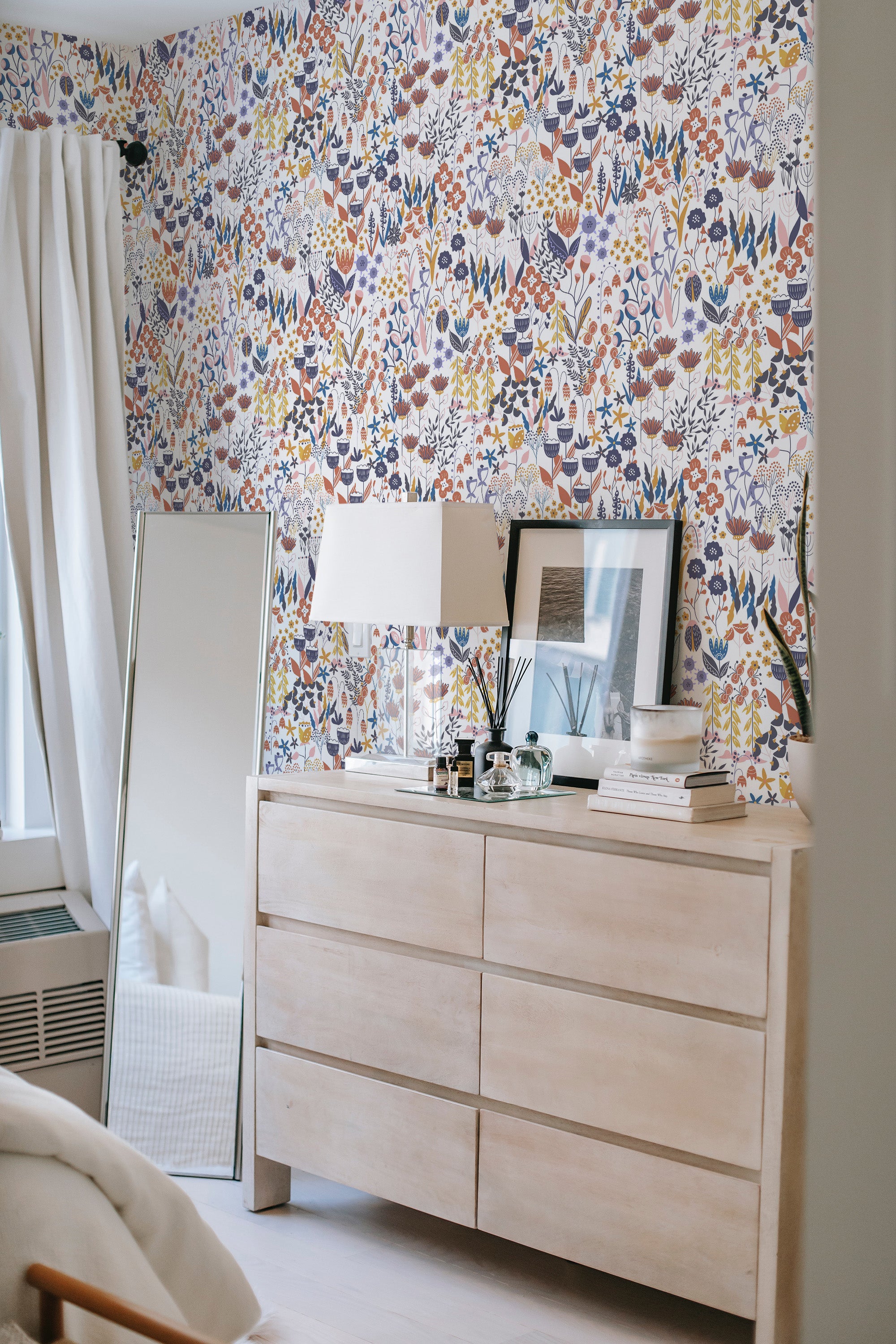 Colorful floral meadow wallpaper filled with intricate flowers, leaves, and plants in rich, vibrant hues of red, blue, orange, and green on a white background, giving a lively and classic feel to the room's atmosphere. Traditional wallpaper.