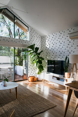 Wallpaper with a pattern of black Husky silhouettes lined up against a white background, creating a clean, modern contrast in a bright living room. Traditional wallpaper.