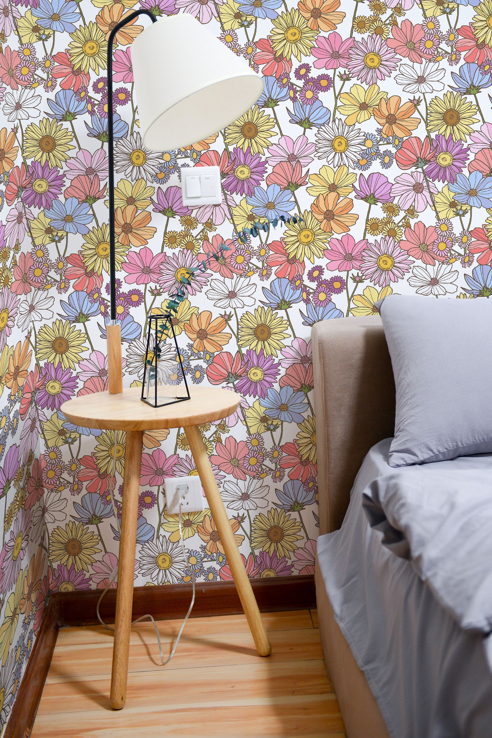 Self-adhesive wallpaper with a vibrant pattern of pastel-colored flowers in shades of pink, yellow, blue, and purple, creating a lively, eclectic floral atmosphere in the room.