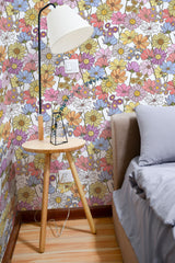 Self-adhesive wallpaper with a vibrant pattern of pastel-colored flowers in shades of pink, yellow, blue, and purple, creating a lively, eclectic floral atmosphere in the room.