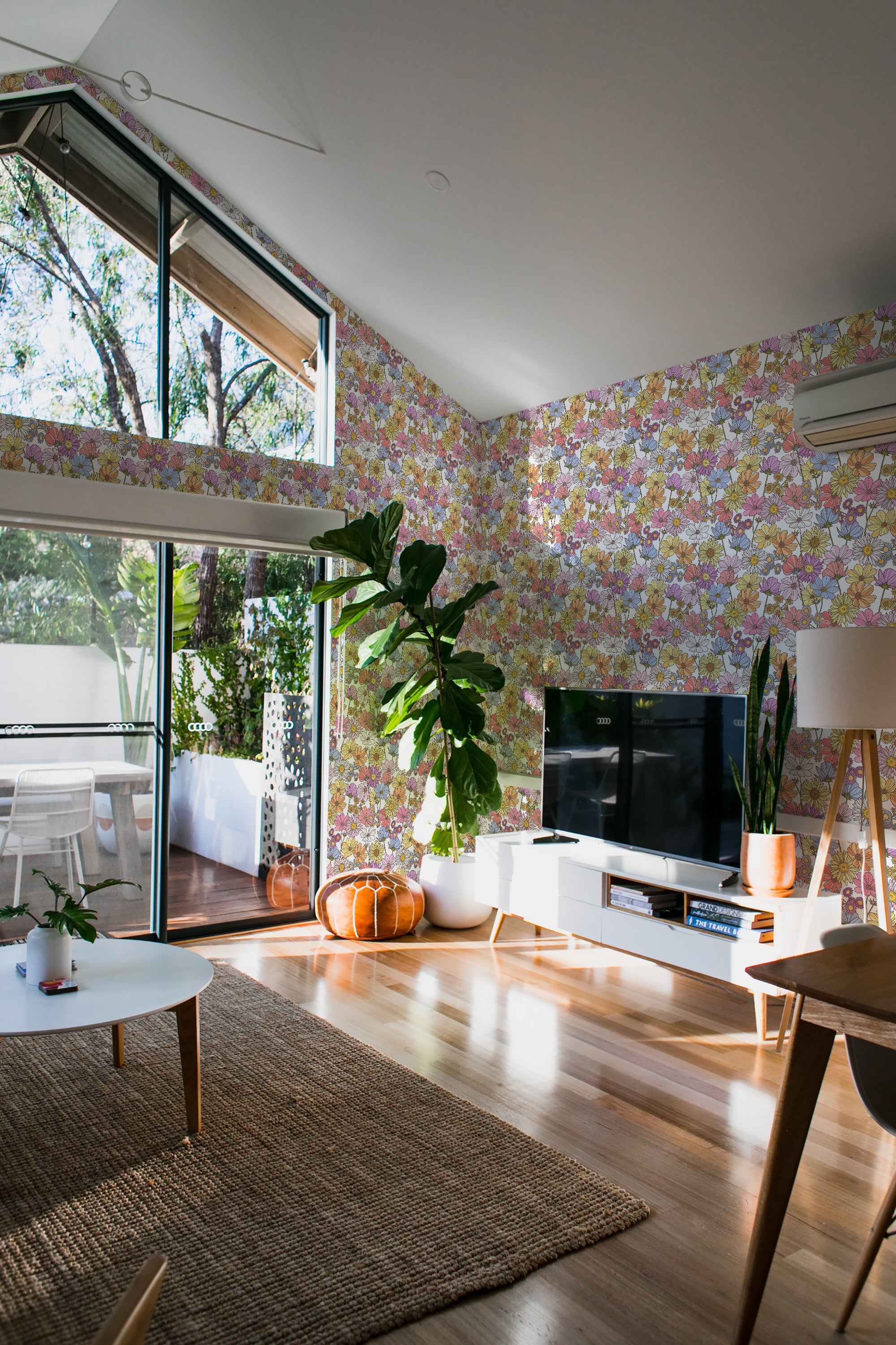 An interior room with walls covered in pastel-colored eclectic floral wallpaper, combining soft pinks, yellows, and greens, enhancing the bright and airy space with a touch of nature and vintage charm. Traditional wallpaper.