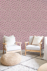 A room with a pink bold eclectic print wallpaper, characterized by intricate patterns of subtle floral and geometric elements, providing a vibrant yet harmonious backdrop. The ornate design adds depth and a touch of creativity to the space, complementing the modern furnishings. The overall aesthetic blends contemporary and vintage styles seamlessly with traditional wallpaper.