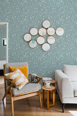 A room with a teal-colored wallpaper adorned with white, delicate vertical lines and small dot patterns arranged in a linear fashion, complementing the traditional wallpaper.