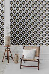 A room with wallpaper featuring a pattern of black star-shaped tiles interspersed with small yellow accents, creating a geometric design against a white background. It is traditional wallpaper.