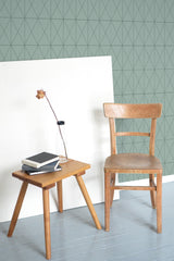 Self-adhesive wallpaper with green geometric tile design, featuring a repeating pattern of overlapping black triangles on a muted green background.