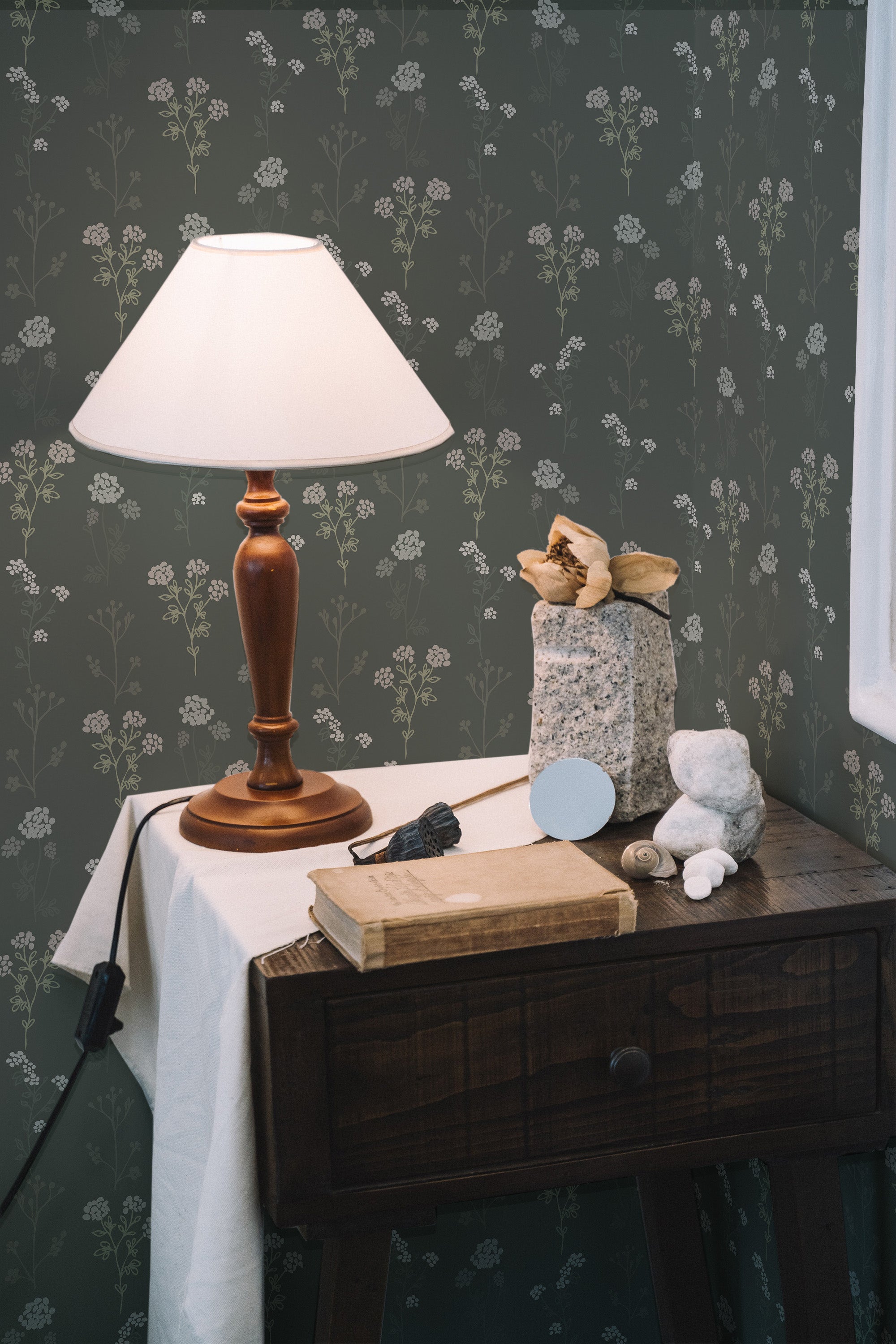 Self-adhesive dark green Scandinavian wallpaper with a delicate pattern of white floral sprigs, creating a cozy and natural ambiance in the room.