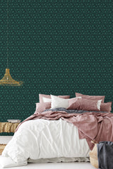 A room with wallpaper in a deep forest green tone adorned with small, repeating circular patterns, creating a retro-inspired aesthetic that complements the cozy bedding and woven light fixture. The traditional wallpaper.