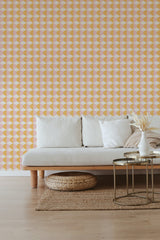 A room with pink and yellow geometric patterned wallpaper with triangles and diamonds, complementing light-toned furniture. Traditional wallpaper.