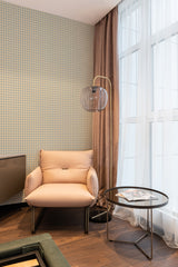 Houndstooth design wallpaper with a classic geometric pattern decorates the wall of a cozy room, paired with light-colored curtains and a soft beige armchair. Traditional wallpaper.