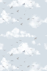Birds flying among fluffy white clouds on a soft blue sky background, creating a serene and airy ambiance. Peel and stick removable wallpaper.