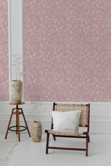 Pink wallpaper with a delicate pattern of leaves, flowers, and stems in a soft, muted tone adorns the wall, adding a subtle and elegant touch to the room. The design has a timeless aesthetic, creating an inviting and classic atmosphere. Traditional wallpaper.