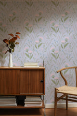 Self-adhesive wallpaper with a design of delicate pink meadow flowers scattered among green stems and leaves, set against a soft, neutral background.