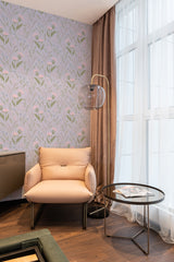 A room with soft pink meadow flowers and green foliage pattern wallpaper on the wall, creating a cozy, nature-inspired atmosphere near a lounge chair and glass-top table. Traditional wallpaper.