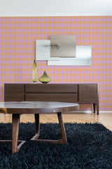 Pink and orange Harlequin pattern wallpaper in a diamond geometric design with alternating pink and orange shades, creating a vibrant, bold look on the wall behind modern furniture. Traditional wallpaper.