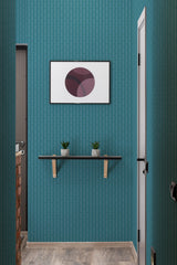 A room with teal-blue subway tile pattern wallpaper and a floating shelf holding two small potted plants beneath a framed modern art piece. Traditional wallpaper.