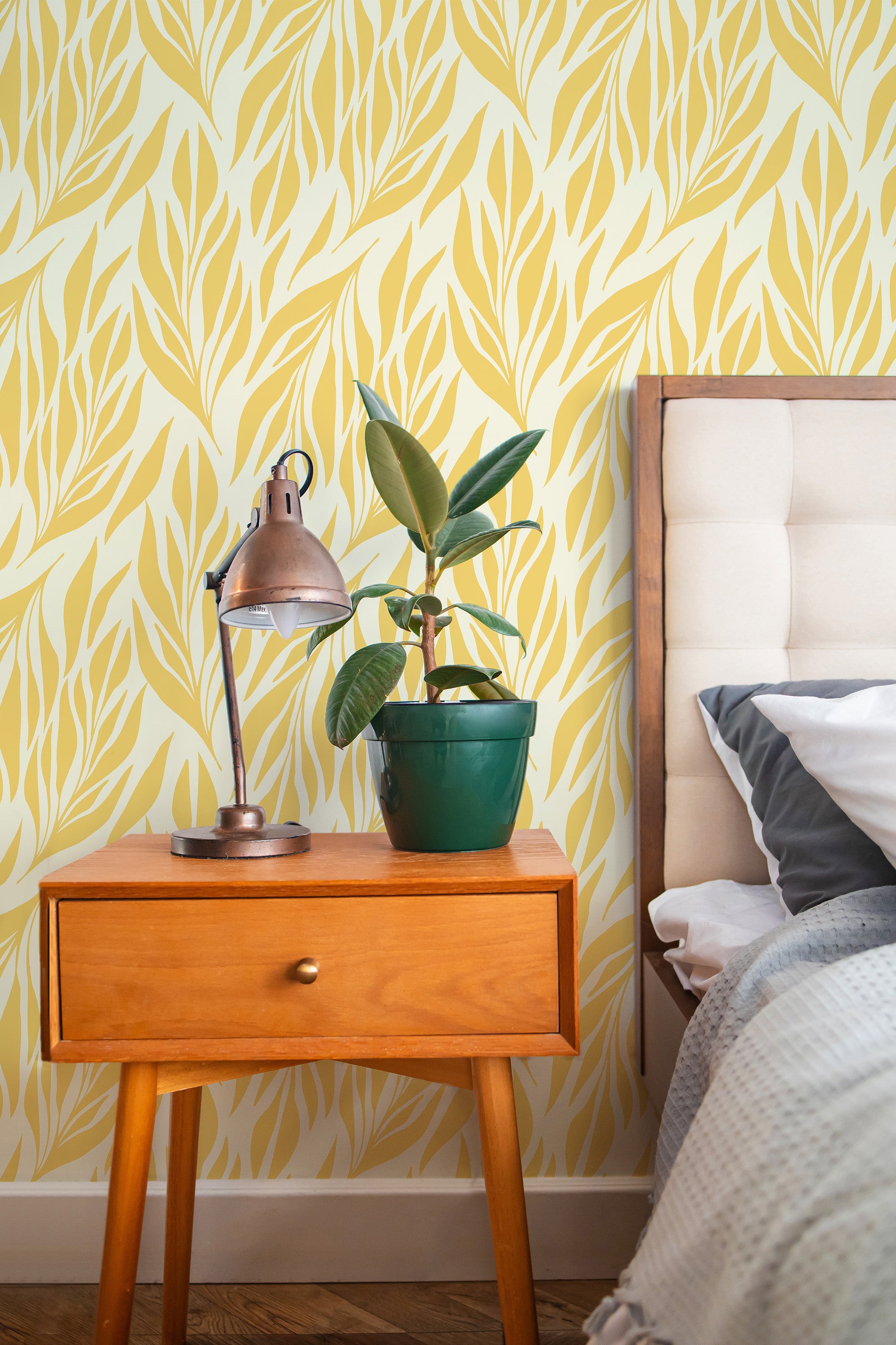 Self-adhesive yellow leaves wallpaper with a repeating pattern of elongated, organic leaf shapes in shades of yellow and white, creating a warm and inviting atmosphere in a modern bedroom setting.