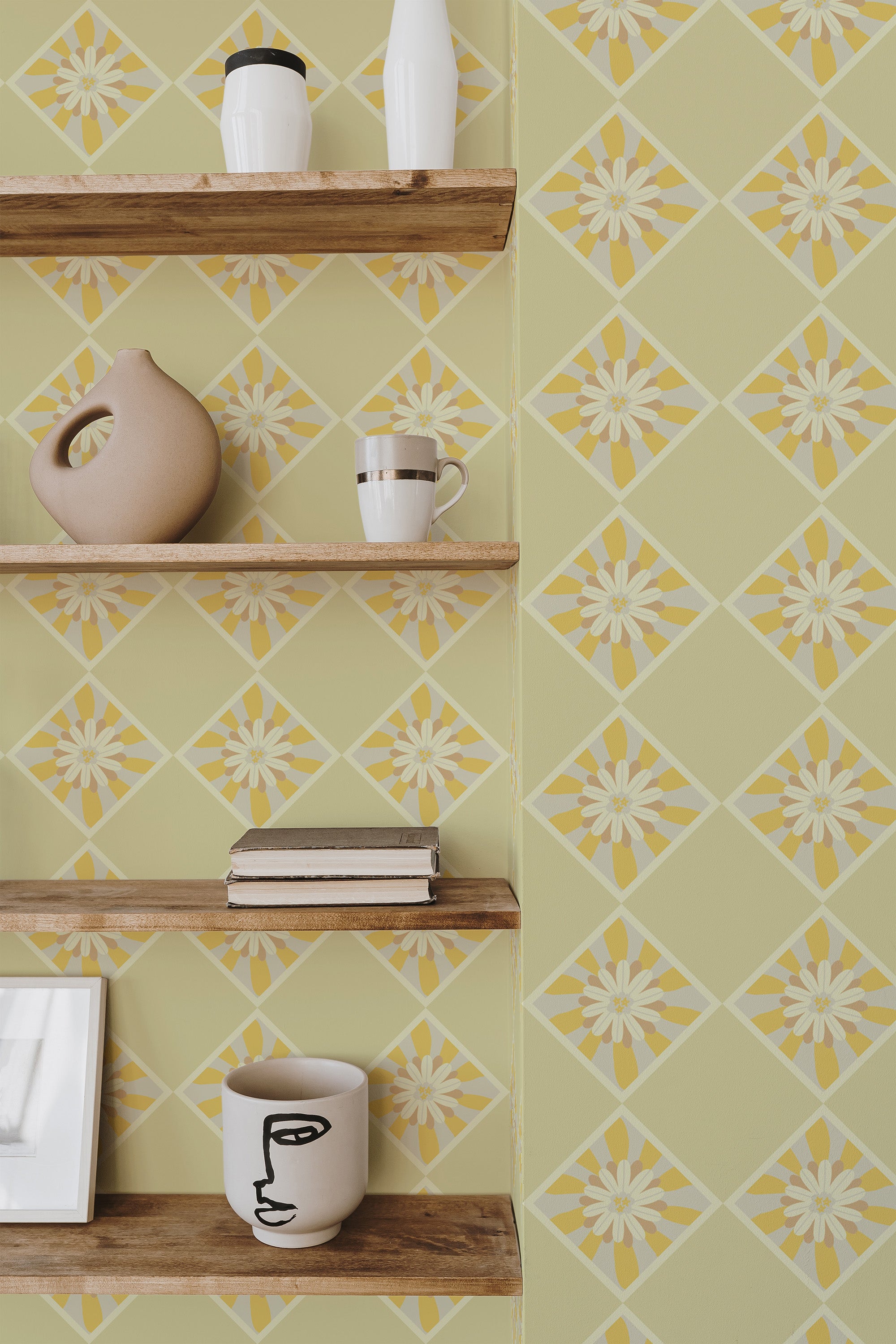 Self-adhesive wallpaper with a sunflower tile pattern in shades of yellow and green on a room wall, complemented by wooden shelves with decorative items.