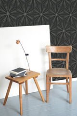 Self-adhesive wallpaper with a sleek black background featuring an intricate pattern of overlapping, geometric starburst designs.