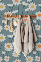 Self-adhesive wallpaper with a Daisy field design, showing large white daisies with yellow centers and green stems on a muted teal background.