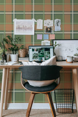 Self-adhesive Autumn farmhouse plaid wallpaper in green and brown tones with a classic check pattern adorning the wall of a cozy workspace with desk and decor.