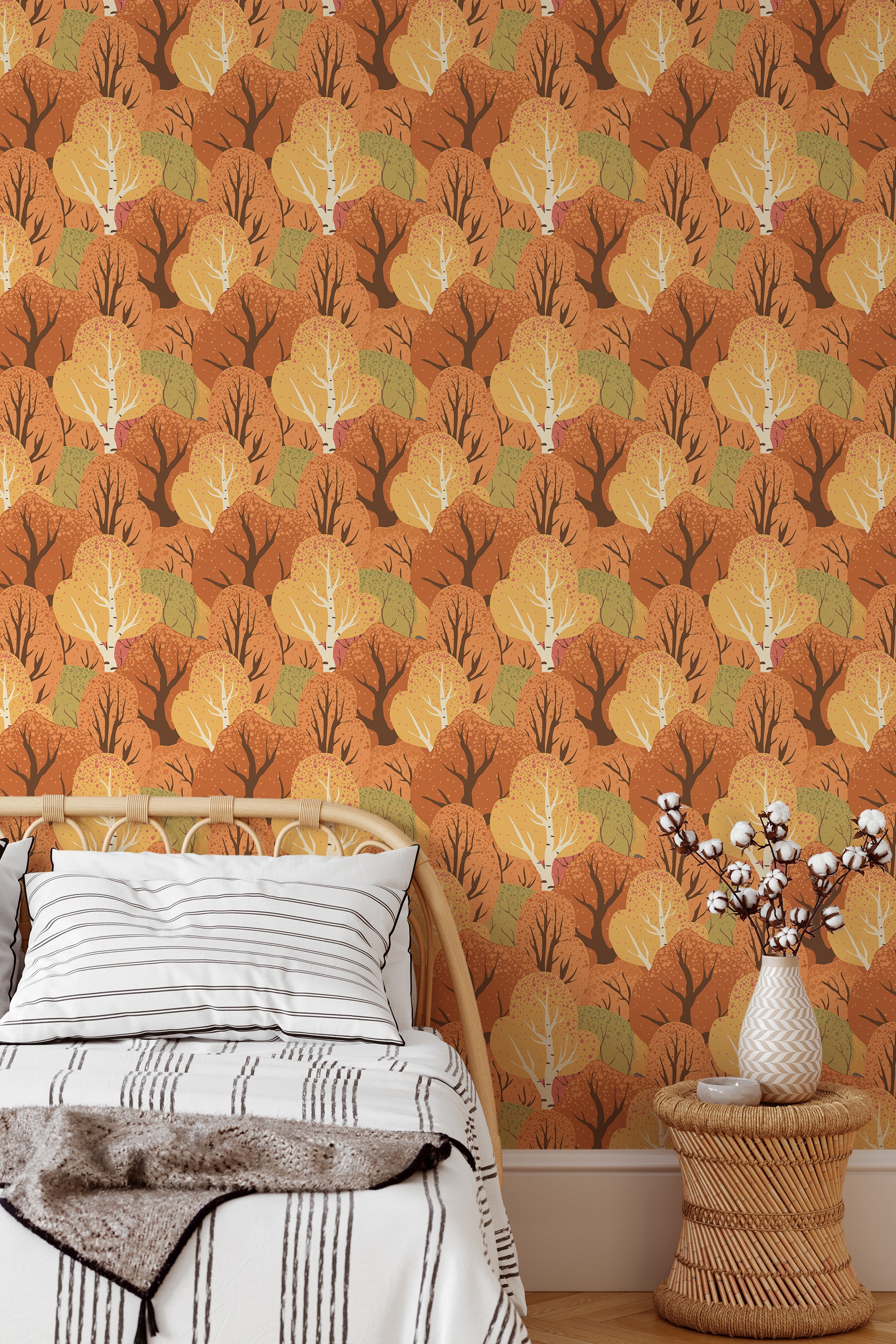 Self-adhesive wallpaper with an Autumn forest pattern of stylized trees in shades of yellow and orange, creating a cozy, warm ambiance in a bedroom with a white bed and vase.