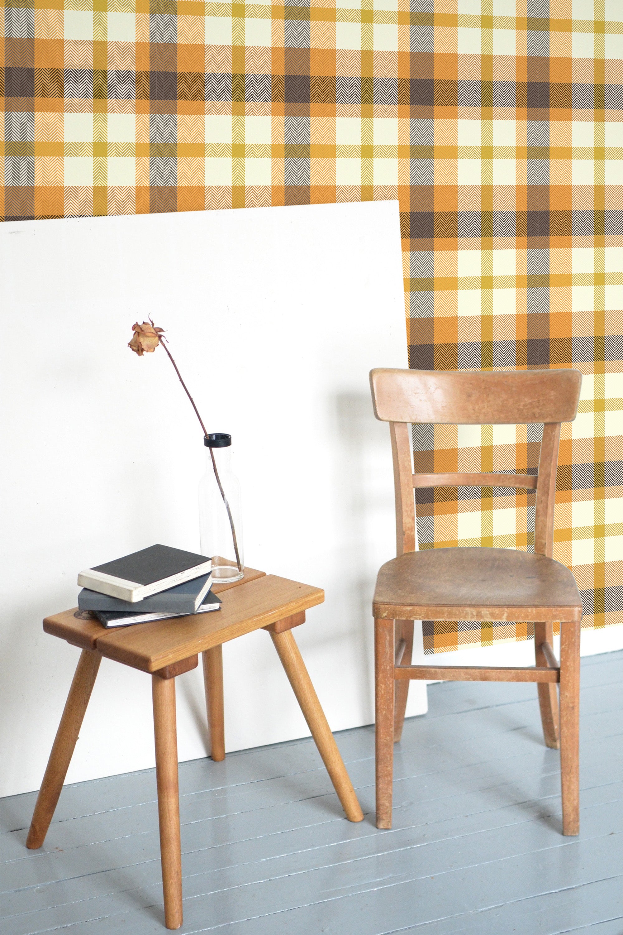 Self-adhesive Orange autumn plaid wallpaper pattern with warm shades of brown and beige, installed on a room's wall behind a wooden chair and table setup.