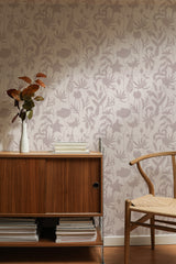Self-adhesive wallpaper with a floral shadows pattern in muted tones on a wall behind a wooden sideboard and chair.