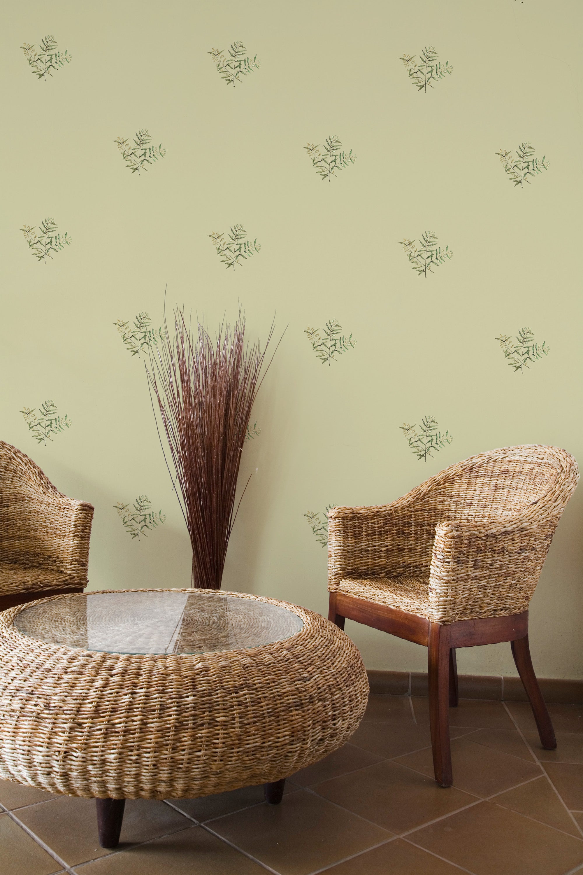 Self-adhesive wallpaper with a pattern of green olives and leaves on a light green background in a room with wicker furniture.