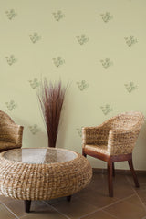 Self-adhesive wallpaper with a pattern of green olives and leaves on a light green background in a room with wicker furniture.