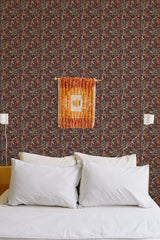 Self-adhesive Burgundy garden wallpaper with intricate floral patterns in shades of red and green, covering a bedroom wall behind a white-pillowed bed.
