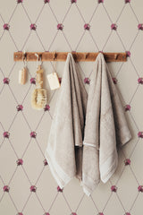 Self-adhesive wallpaper with a repeating vintage tiny rose pattern on a beige background, accentuated by hanging towels and wooden bathroom accessories.