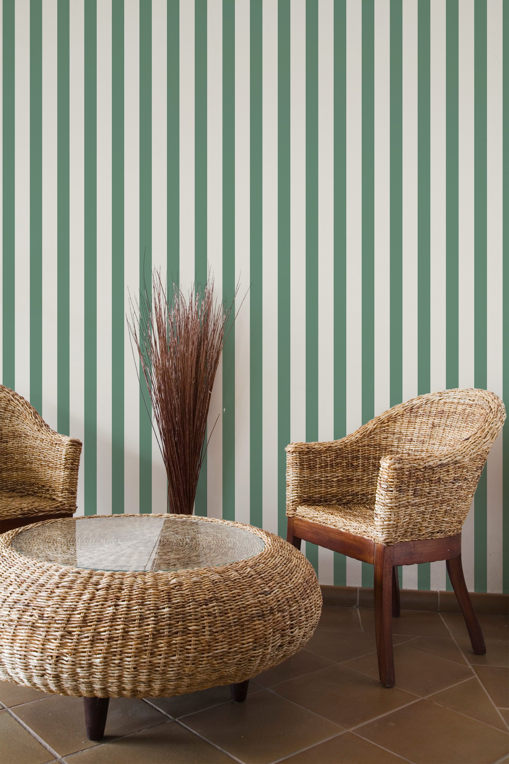 Self-adhesive wallpaper with vertical classic green and white stripes in a room, complemented by wicker furniture and a decorative dried plant.