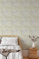 Self-adhesive Elegant Strokes wallpaper with subtle, organic brush patterns in soft green hues on a bedroom wall, complementing a natural wood bed and wicker vase with branches.