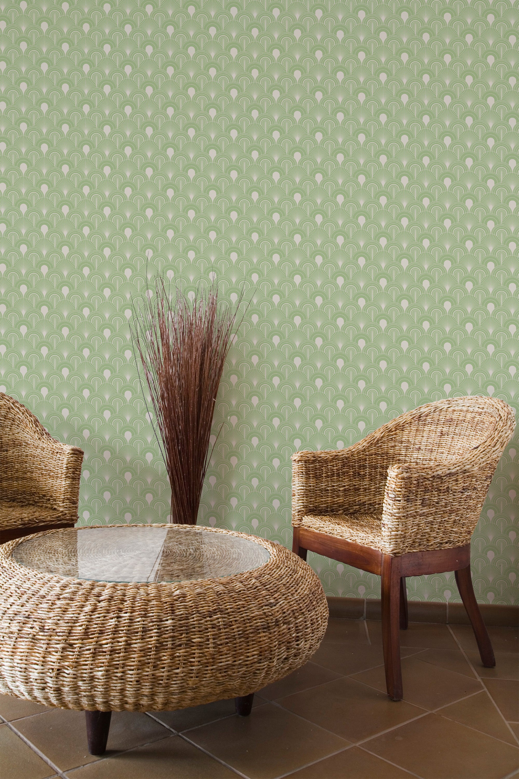 Self-adhesive Olive Art Deco wallpaper with symmetrical fan shapes in a repeating pattern on a room wall, accompanied by wicker furniture and a vase of dried branches.