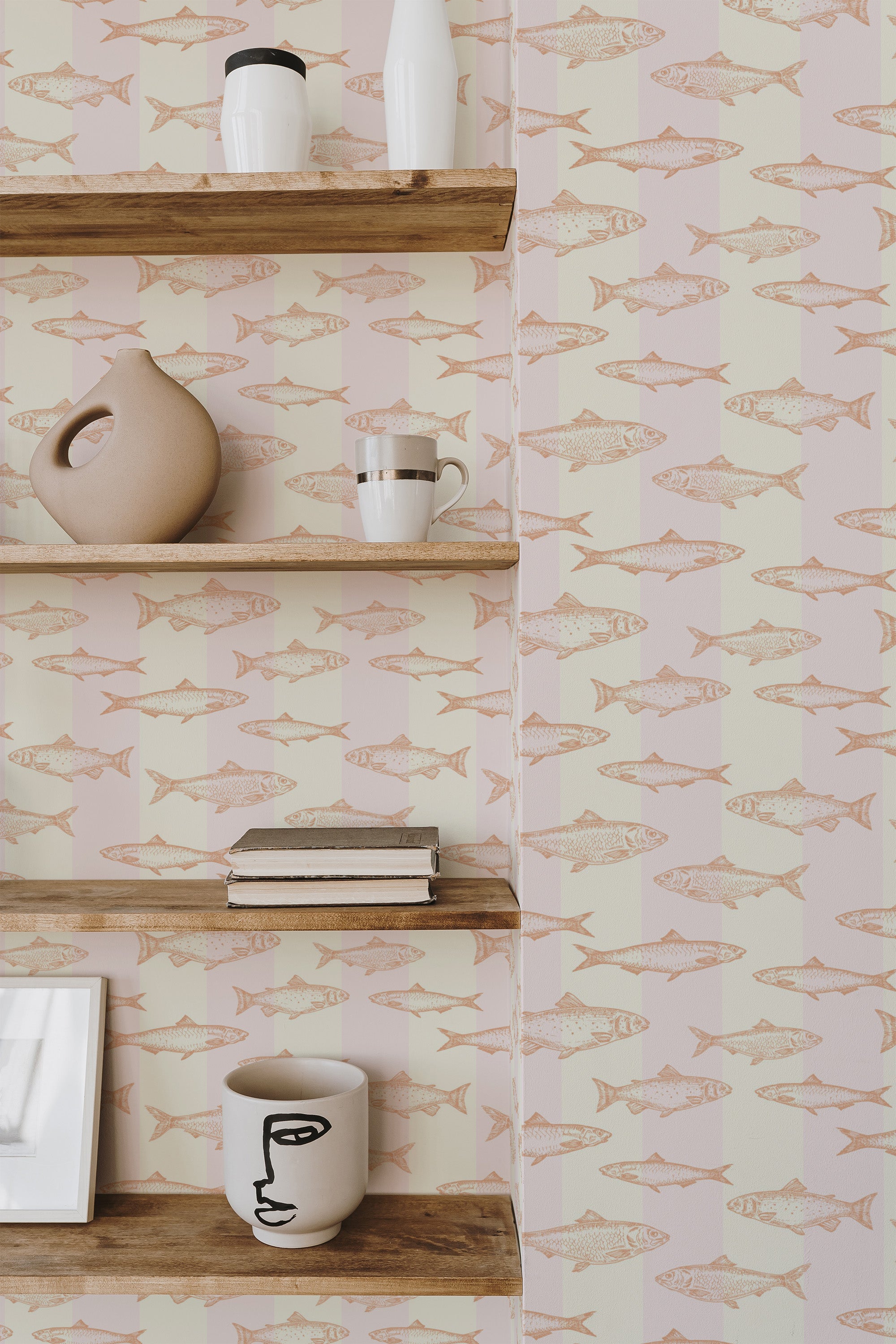 Self-adhesive wallpaper with a peachy fish pattern on a pale pink background, displayed in a room with wooden shelving and decorative items.