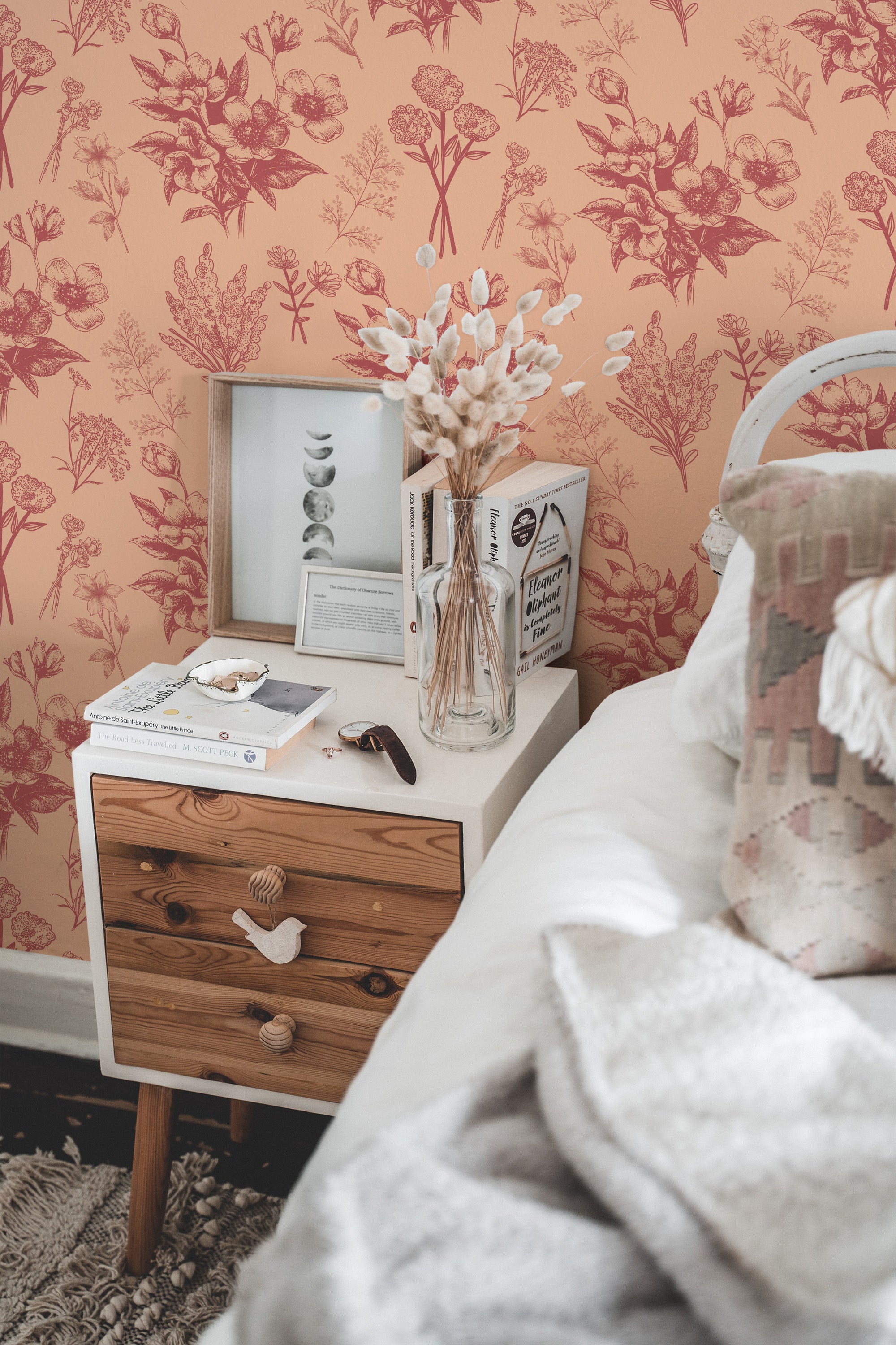Self-adhesive wallpaper with Delicate Flower pattern in shades of orange and red, covering a bedroom wall with a wooden nightstand and decorative items.