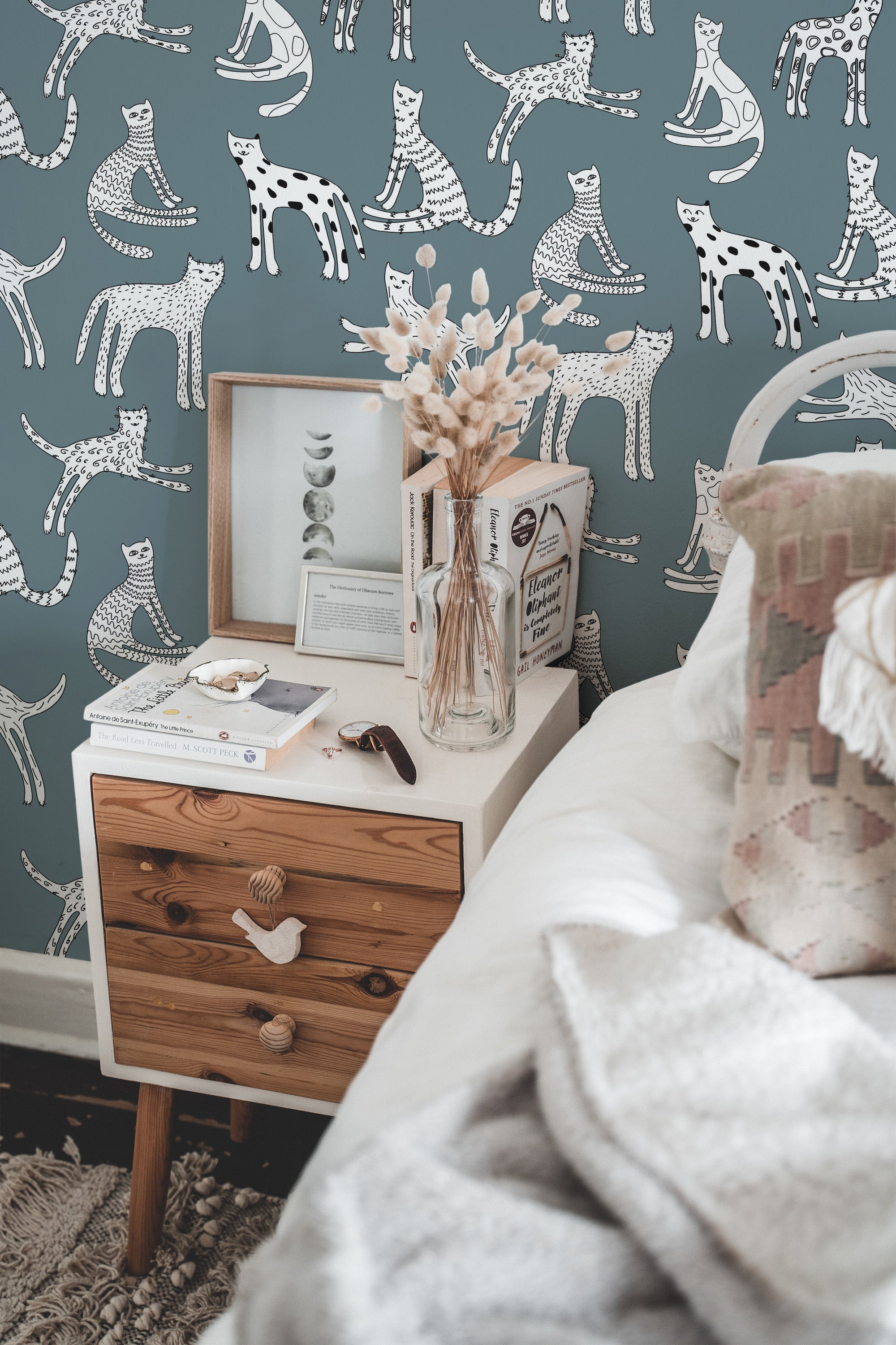 Self-adhesive wallpaper with a Cute Kitten pattern on a bedroom wall, with illustrations of playful kittens in various poses on a teal background.