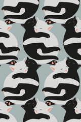 Black and white cats cuddling in a repeated pattern on a pale green background, peel and stick removable wallpaper.