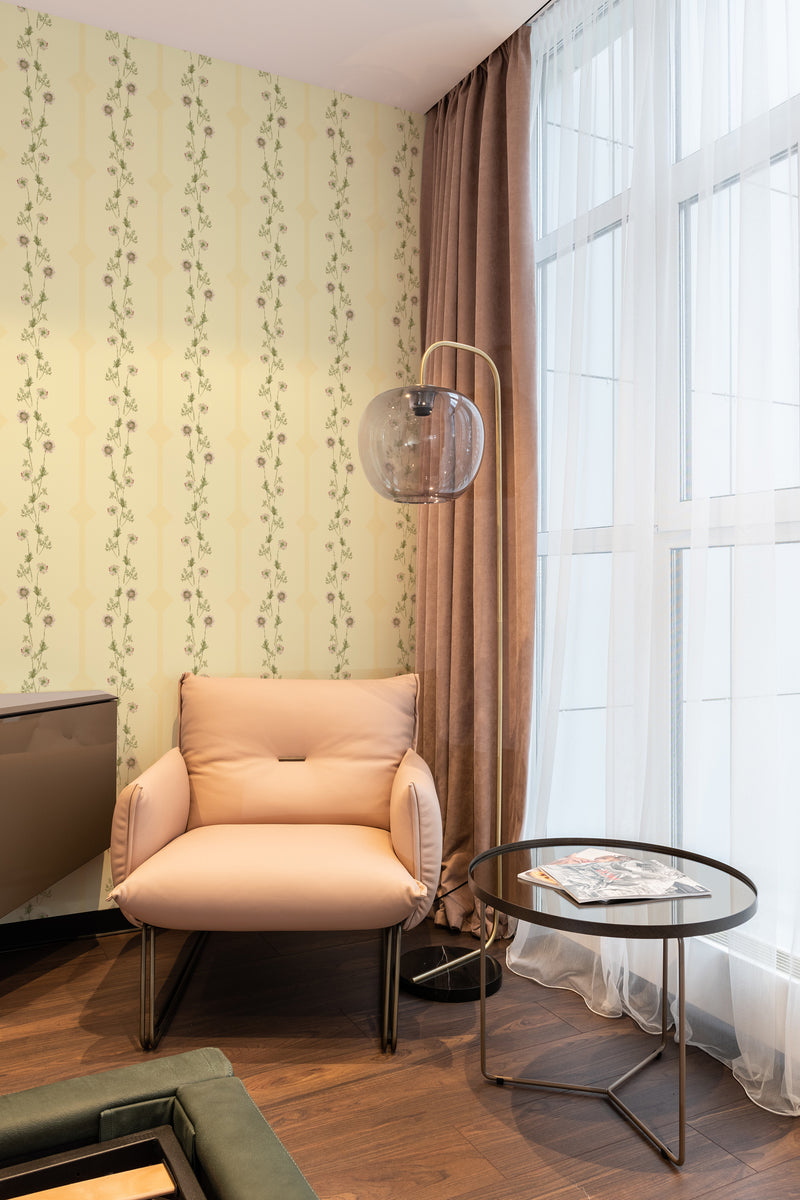 Wallpaper with a soft yellow background and vertical green vine-like geometric flower line patterns in an elegant design, creating a sophisticated ambiance in the room. Traditional wallpaper.