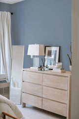 A room with a solid dusty blue wallpaper covering the wall, creating a calm and serene ambiance. Traditional wallpaper.