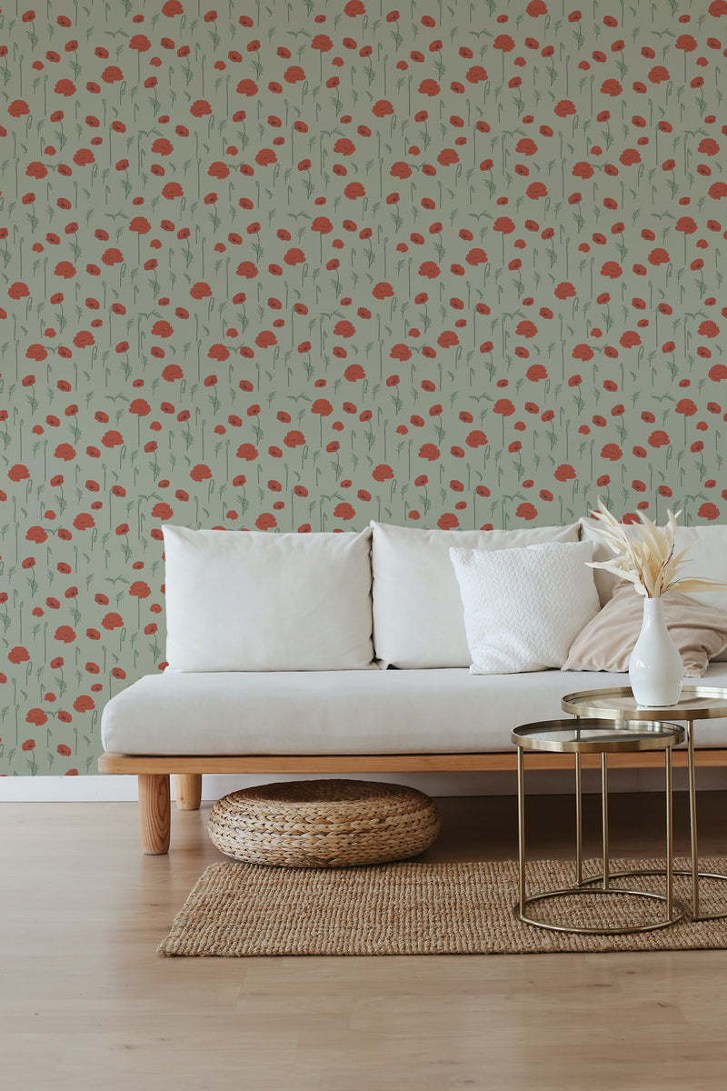 The wallpaper has a repeating pattern of red poppies and green stems set against a neutral background, evoking a serene meadow scene in a cozy room with natural wood accents and a light beige couch. Traditional wallpaper.