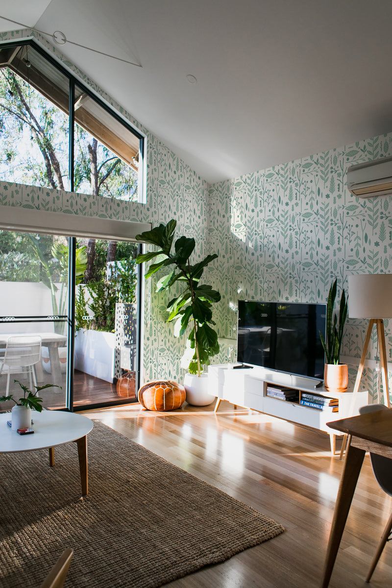 Light and airy room with Scandinavian plant wallpaper, including stylized green foliage patterns on a pale background, complementing natural light and modern decor. Traditional wallpaper.